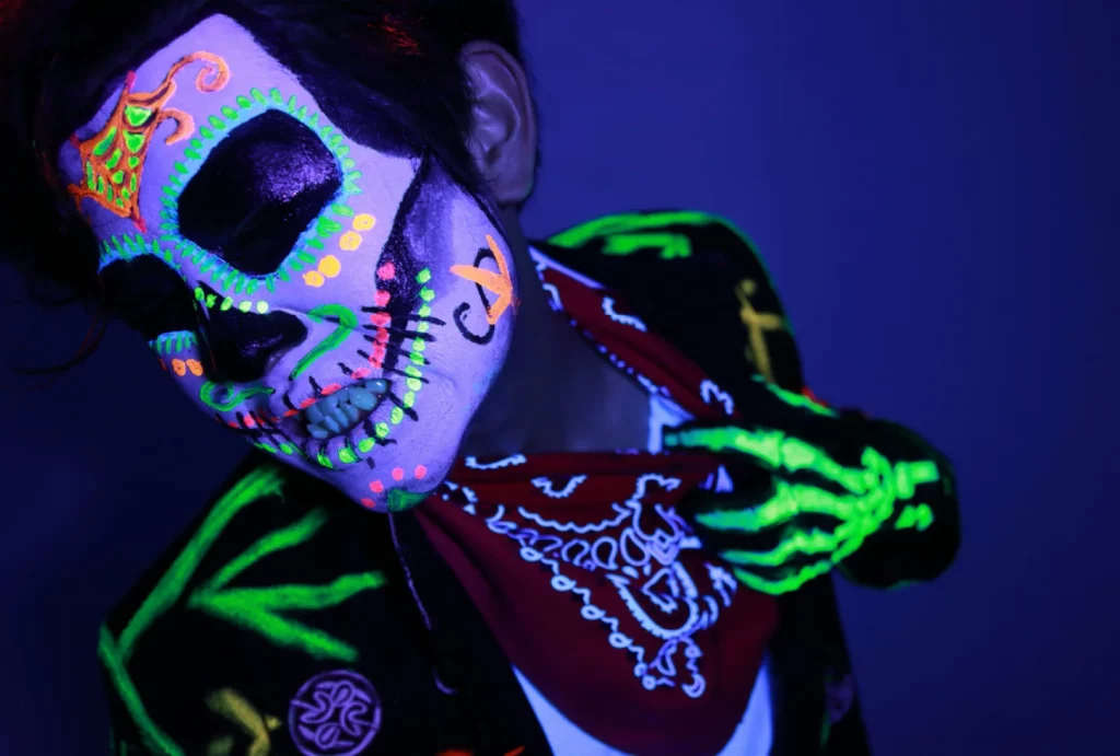 A person in elaborate glow-in-the-dark Día de los Muertos face paint.