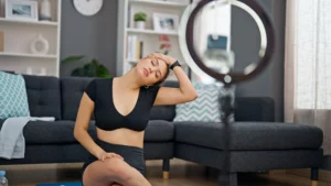 A woman recording a neck stretching video in her living room.