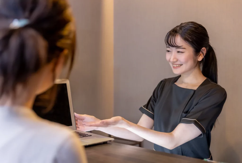 A massage therapist presenting a tablet to a client at the reception area of a spa.