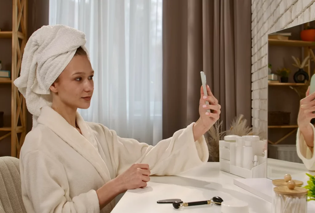 A girl in a robe and a head towel taking a selfie