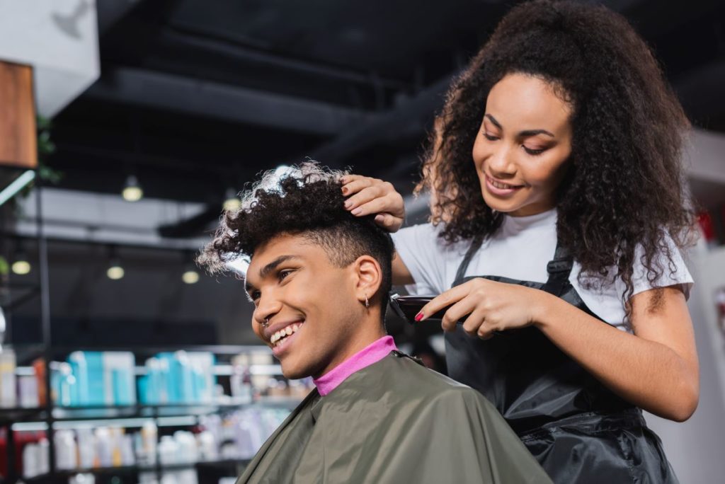 Hairstylist uses trimmer on client's hair