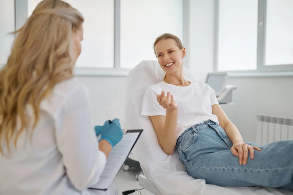 An esthetician takes notes on a clipboard while speaking to a client at an esthetics studio.