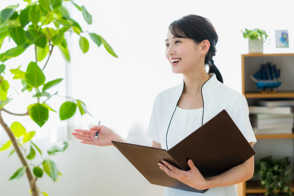 An esthetician smiles while holding a brown folder and pen at a skincare studio.