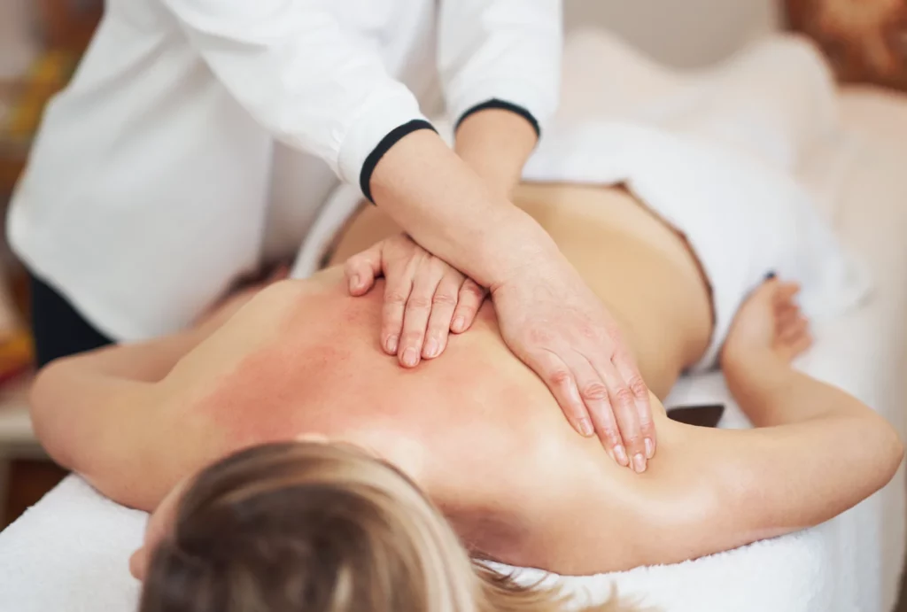 A massage therapist performing a back massage on a client with an area of slightly reddened skin.
