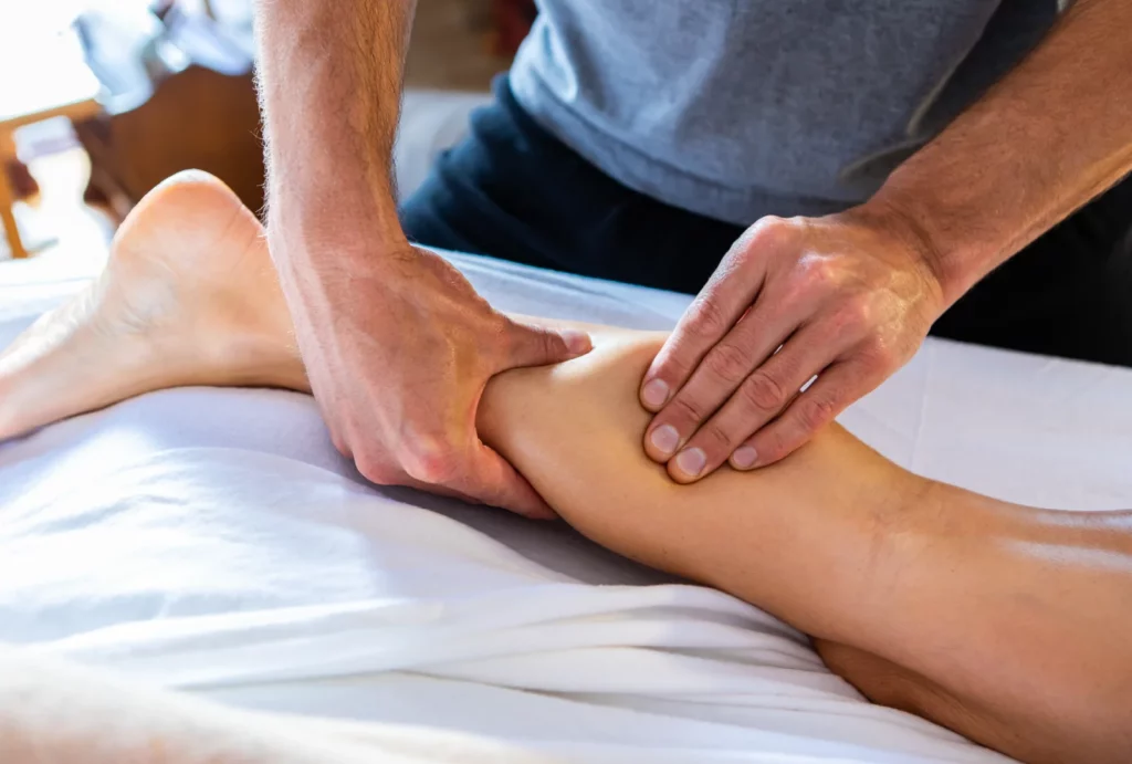 Close-up of a massage therapist working on a client's calf muscle.