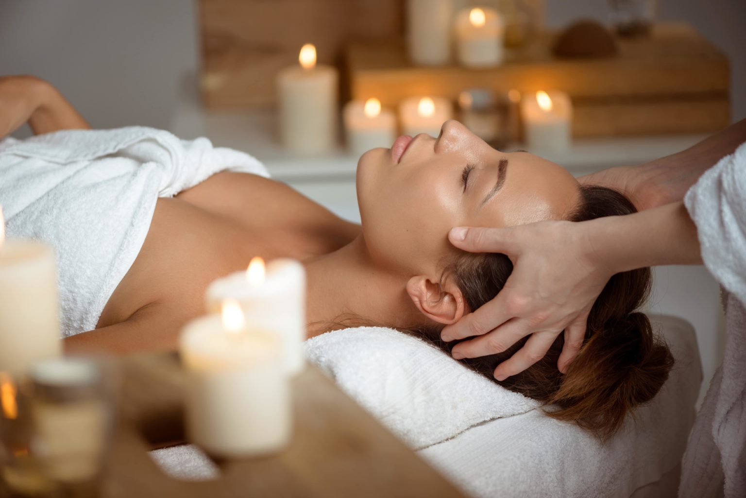 young woman having face massage relaxing in spa salon