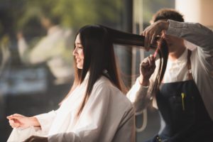 woman with long hair smiling getting hair cut in salon