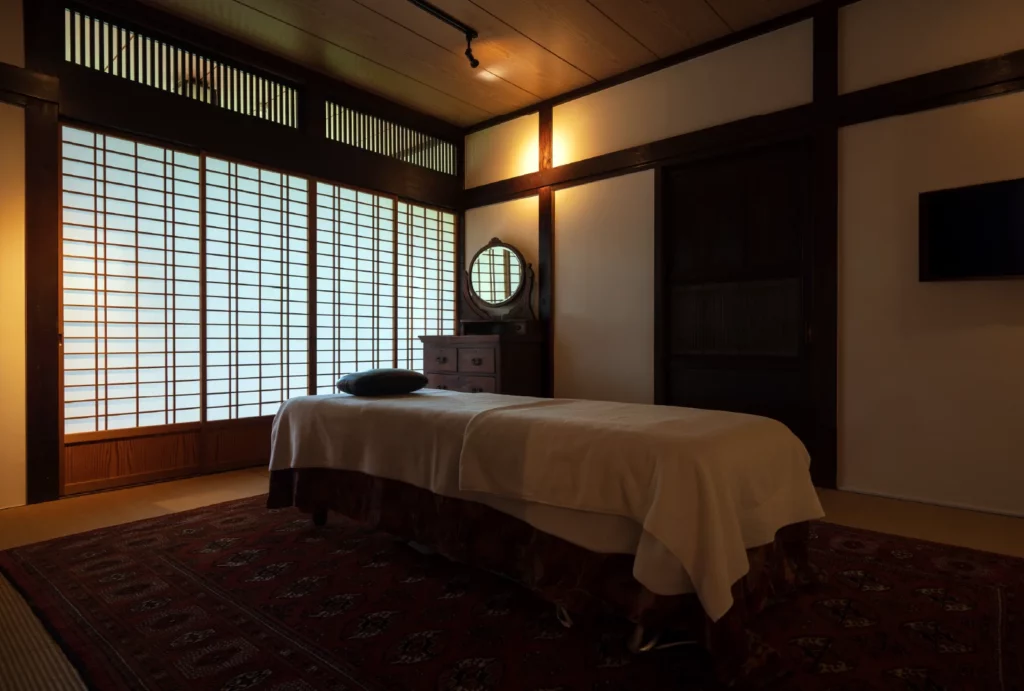 Peaceful massage room with a massage table and large windows