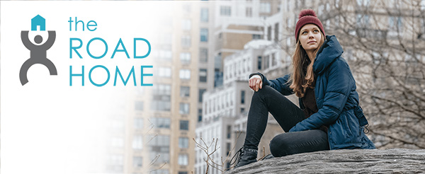 woman sitting on a rock in the city - the road home logo