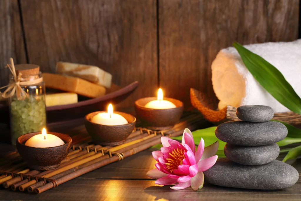 Lit candles, a flower, and stacked stones on a table