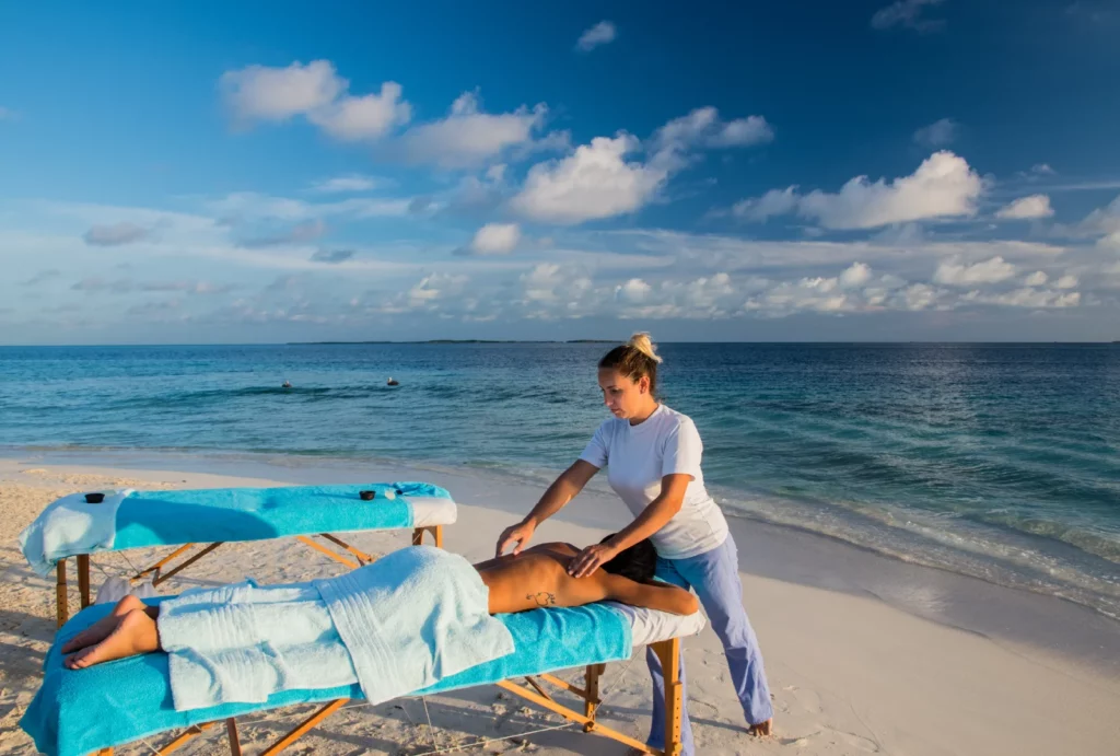 A woman giving a man a massage on the beach