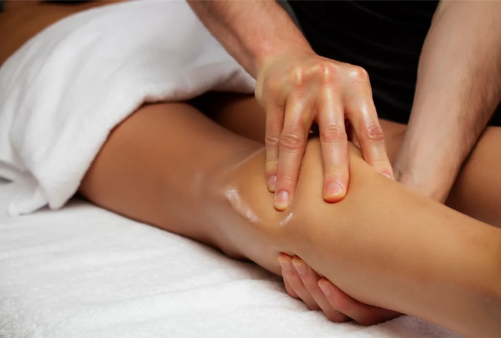 A pair of hands massaging a calf on a massage table
