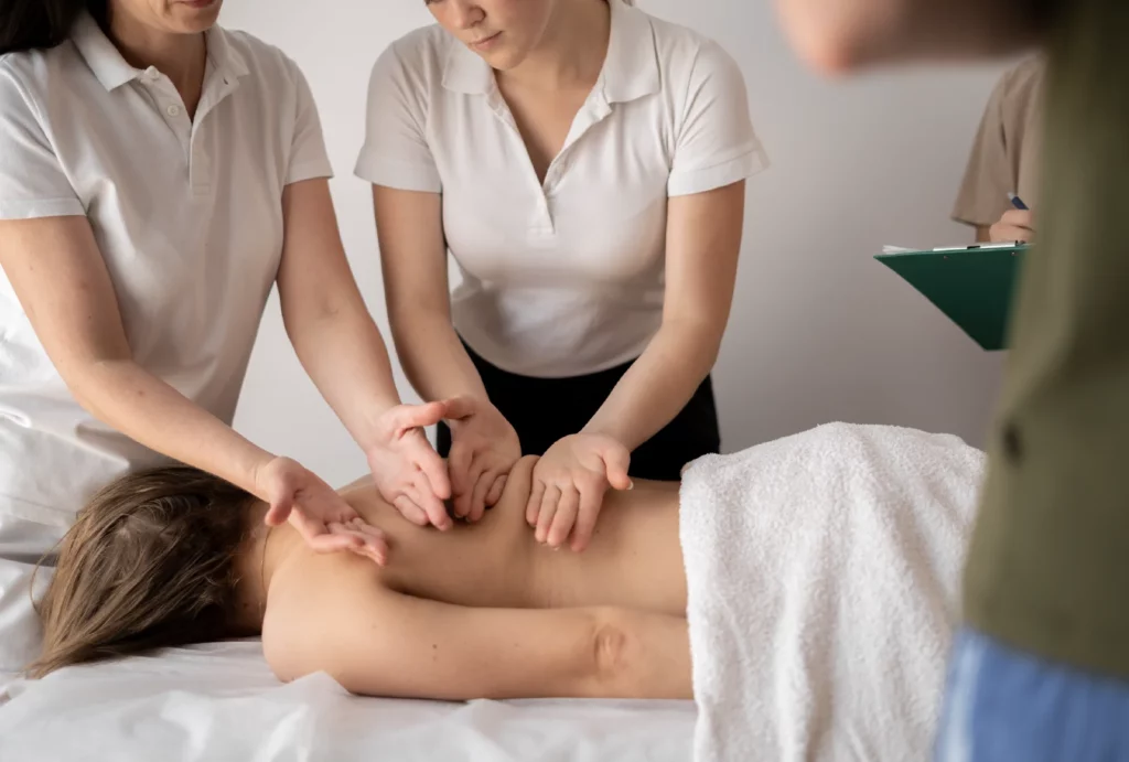 A massage instructor showing a student how to massage a patient