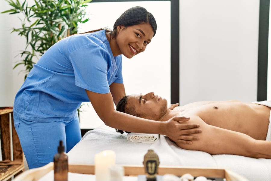 woman giving man massage on table smiling at camera