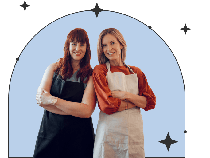 two women standing back to back smiling