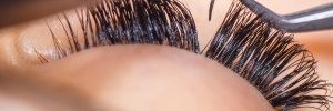 estheticians placing eyelash extensions on clients eye lid