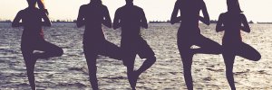 group of people doing yoga on the beach