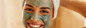 woman smiling with green face mask on