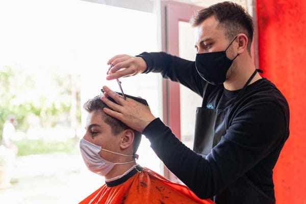barber cutting male clients hair with scissors