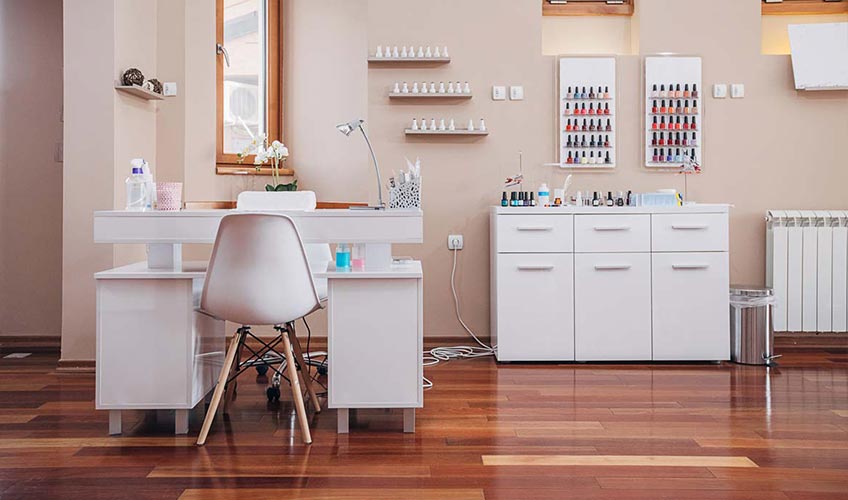 view of a nail salon table, chairs and nail polish options