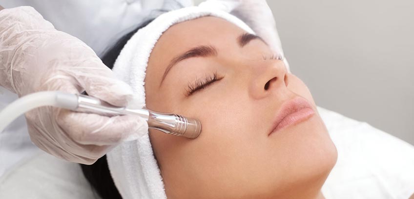cosmetologist giving client a microdermabrasion facial