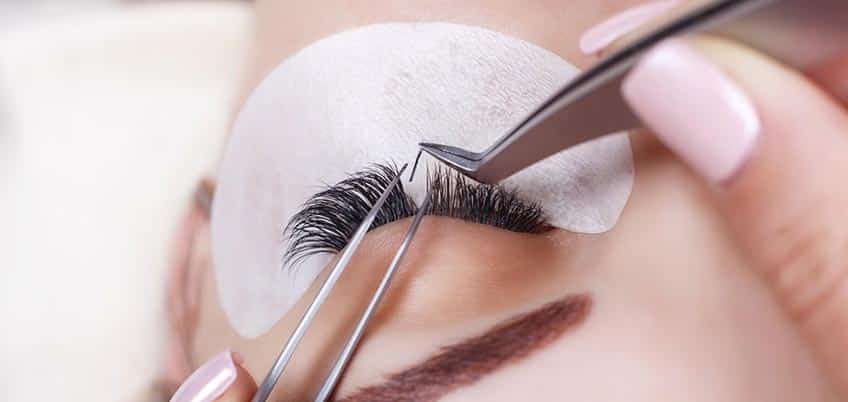 cosmetologist applying lash extensions