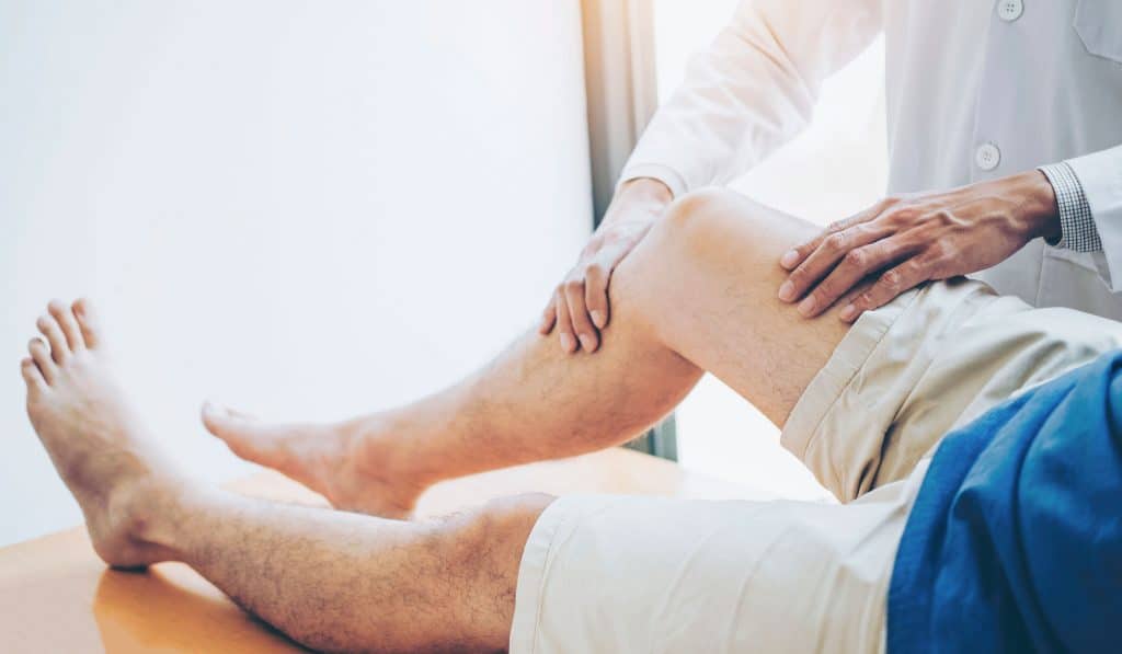 sports massage therapist assessing mans leg pain