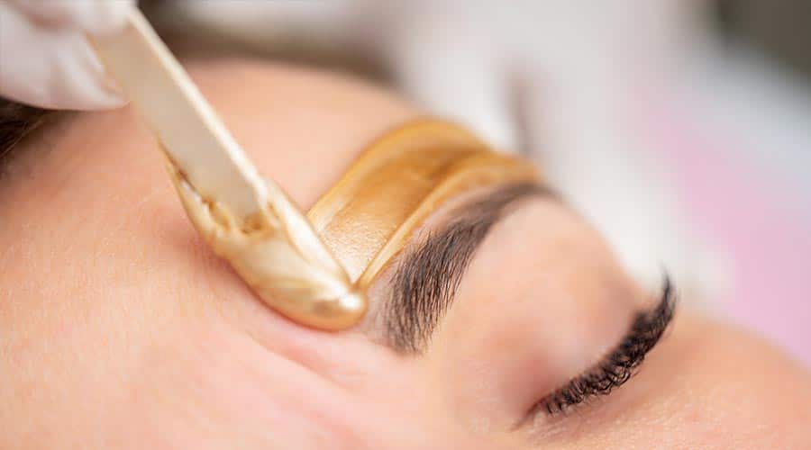 woman getting her eyebrows waxed by an esthetician