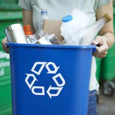 woman taking out full blue recycling bin