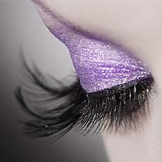 close up of eyelid with long eyelash extensions and purple eye shadow