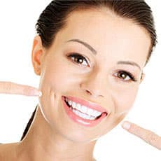 woman smiling and pointing to white teeth