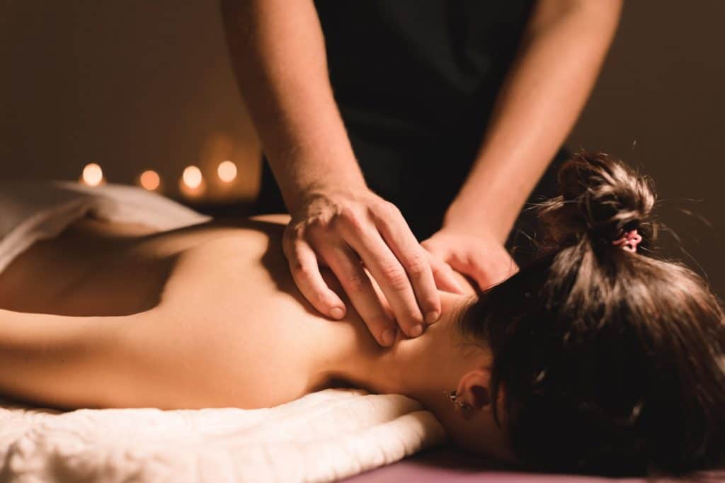 massage therapist giving massage with candles