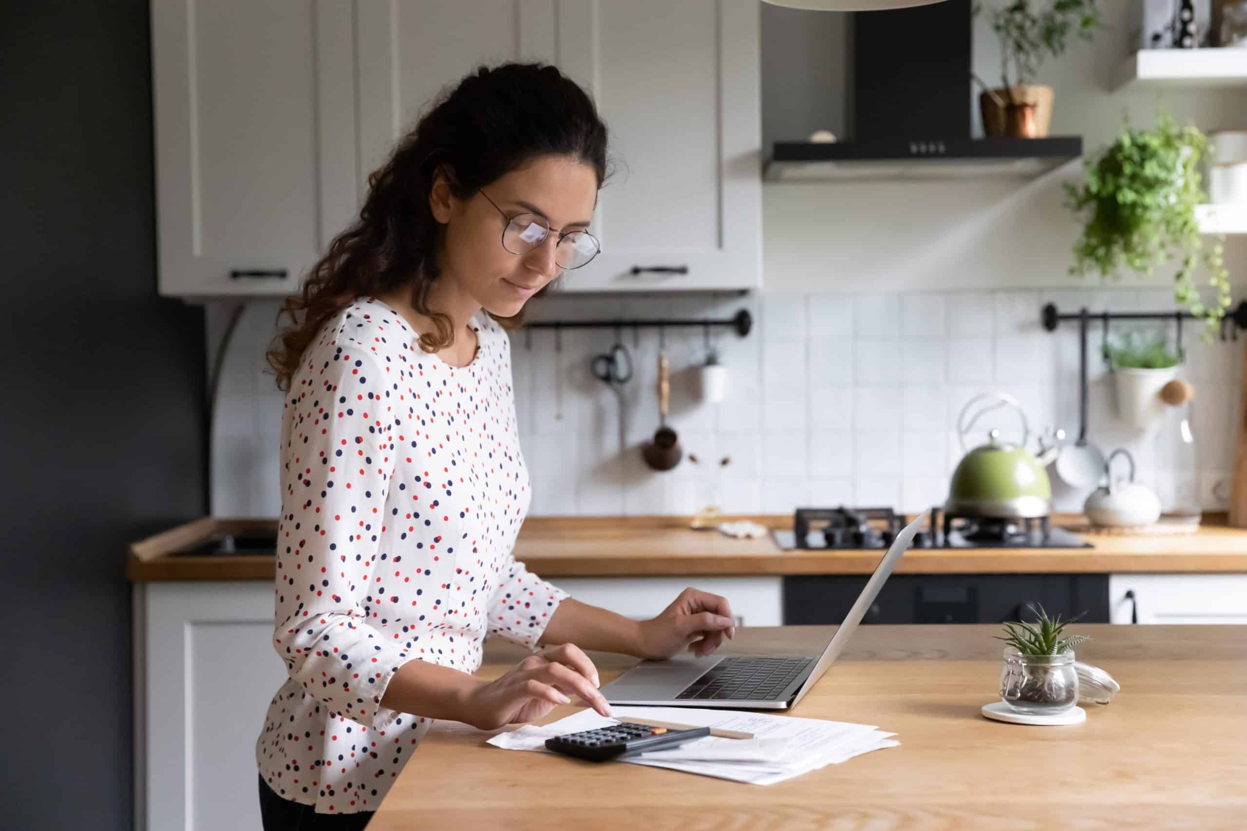woman at kitchen counter doing taxes with computer